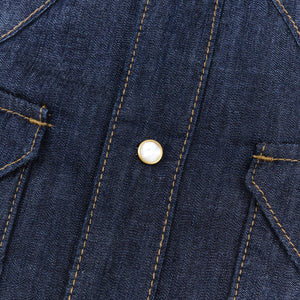 Dark indigo denim western-style shirt with white snaps, close up on snap, laying flat