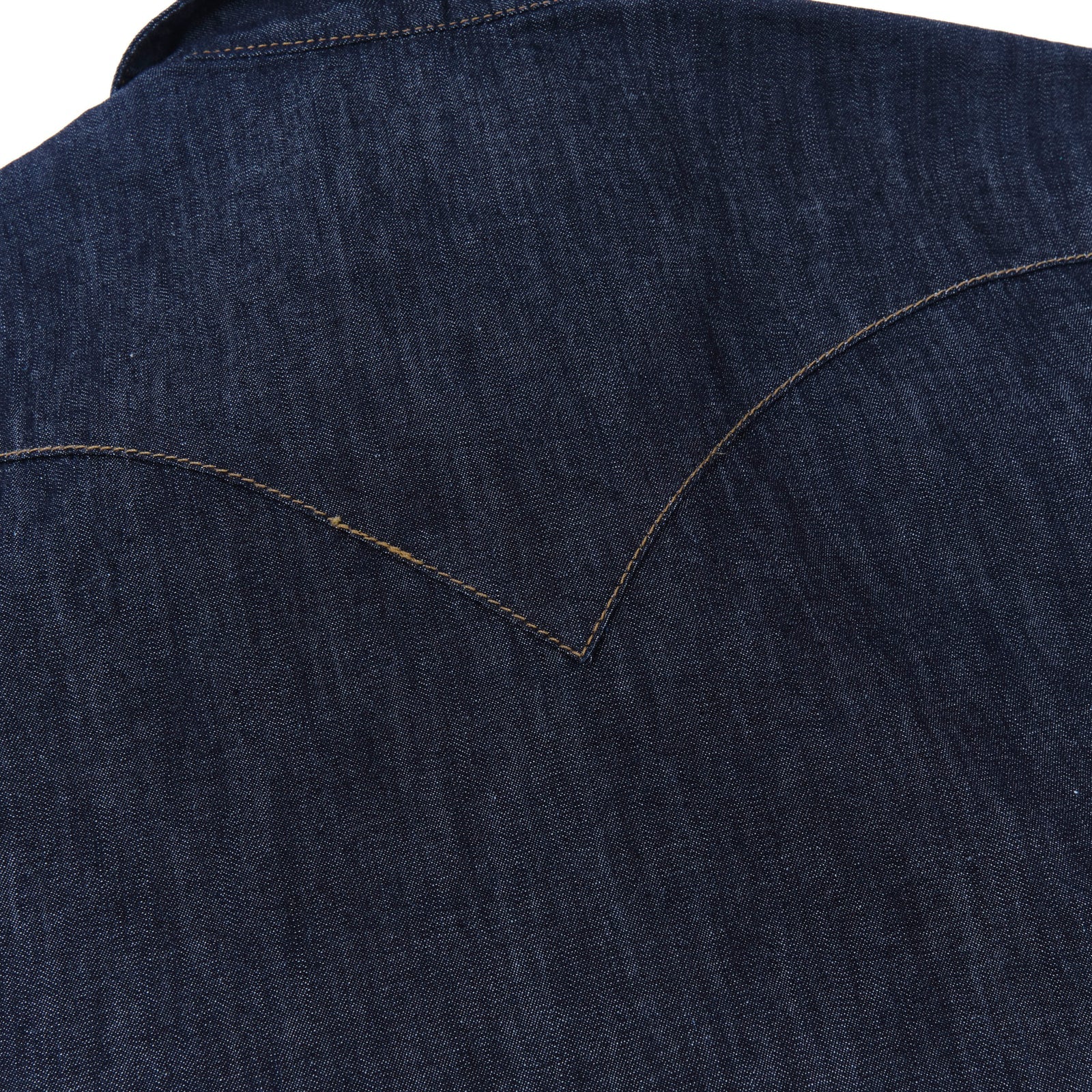Dark indigo denim western-style shirt with white snaps, close up on back yoke laying flat