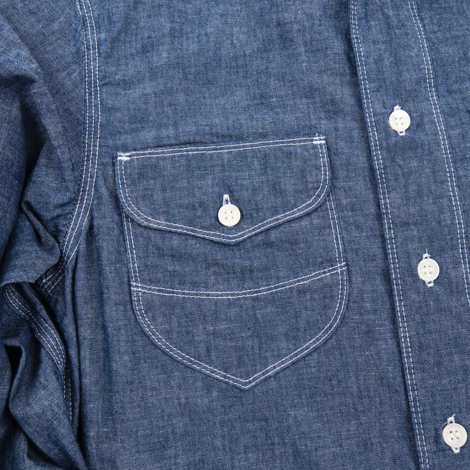 Shirt laid flat on white, from the front. Close up on right chest pocket. 