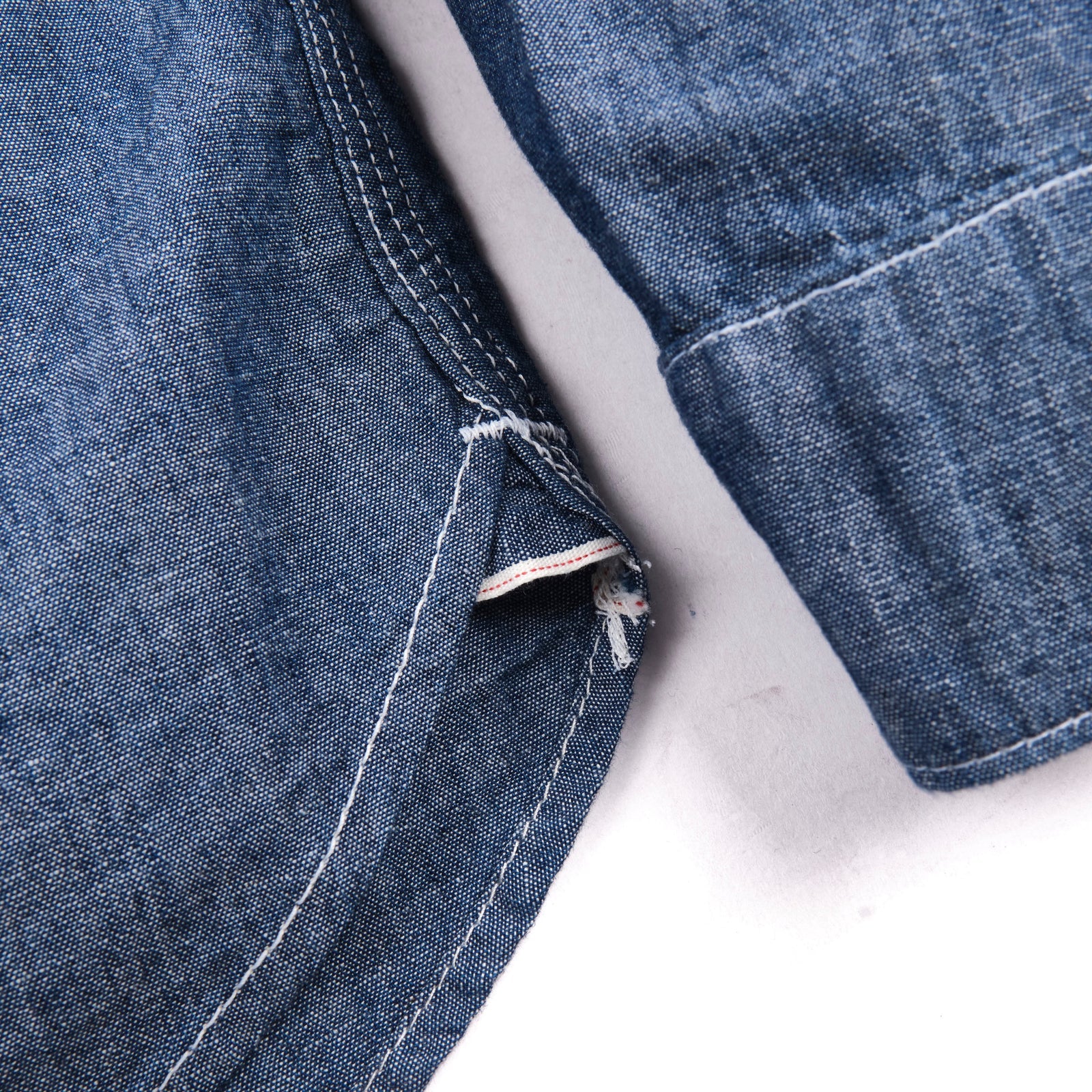 Shirt laid flat on white, from the front. Close up on bottom hem, with selvedge ID
