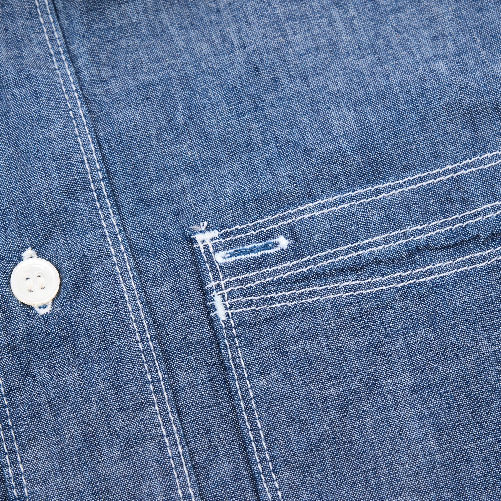Shirt laid flat on white, from the front. Detail on left chest pocket. 