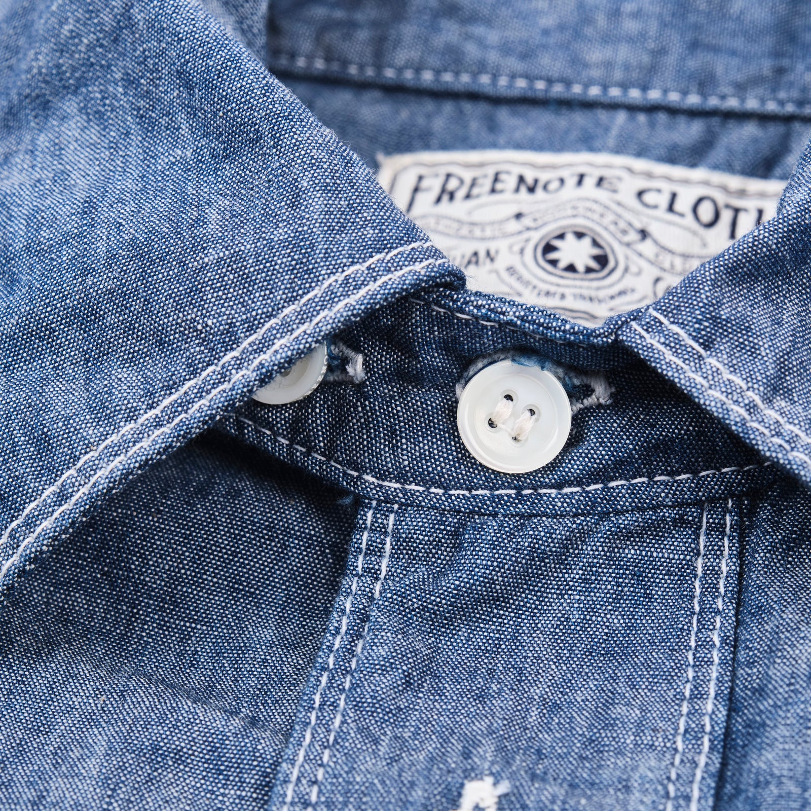 Shirt laid flat, from the front. Close up on collar buttons