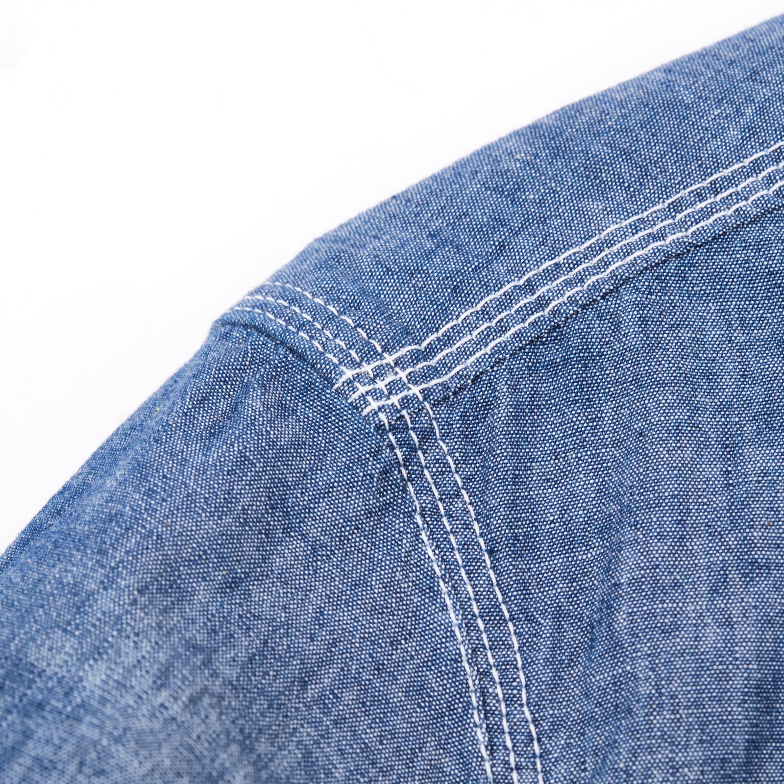 Shirt laid flat on white, from the front. Close up on right shoulder, with triple  stitch. 