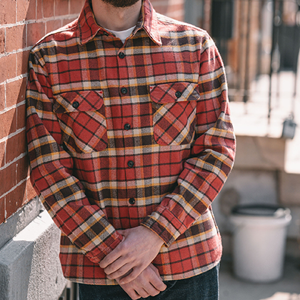 A front view of a model wearing a red and brown flannel