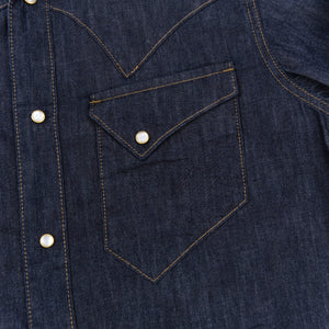 Dark indigo denim western-style short sleeve shirt with white snaps, close up on left chest pocket laying flat